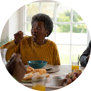 A smiling woman enjoys a meal with her family.