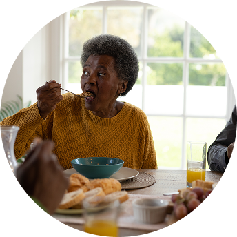 A smiling woman enjoys a meal with her family. A smiling woman enjoys a meal with her family.