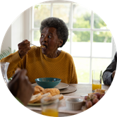 A smiling woman enjoys a meal with her family. A smiling woman enjoys a meal with her family.