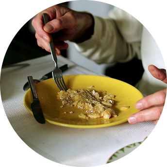 A person eats a meal from a yellow plate.