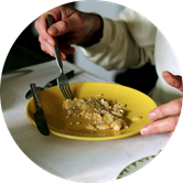 A person eats a meal from a yellow plate. A person eats a meal from a yellow plate.