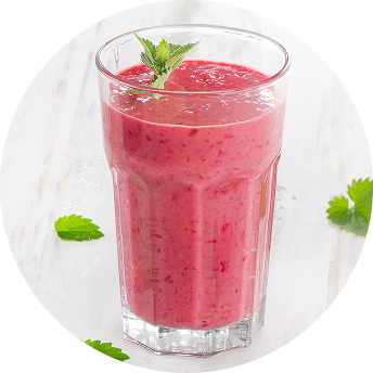 A pink fruit smoothie in a glass cup