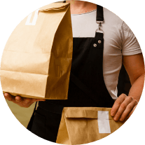 A person in an apron holds paper bags Contact Us Mobile Banner Image
