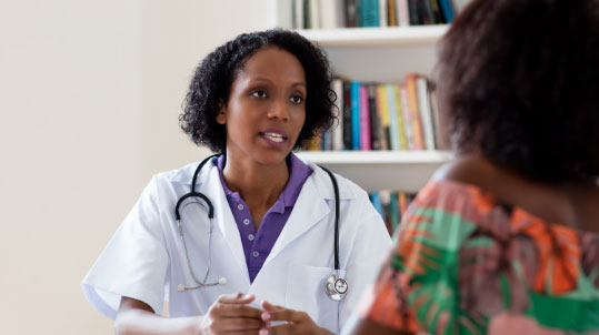 A doctor speaks with a patient in her office Professional Help Promo Image