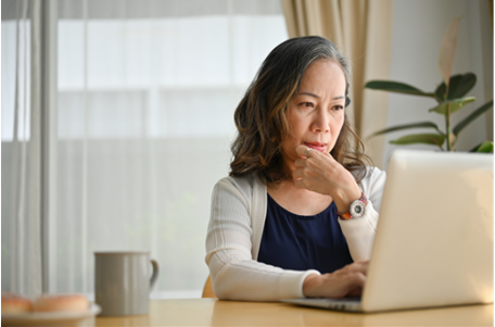 A woman looks at her computer while touching her chin Trusted Sites Promo Image